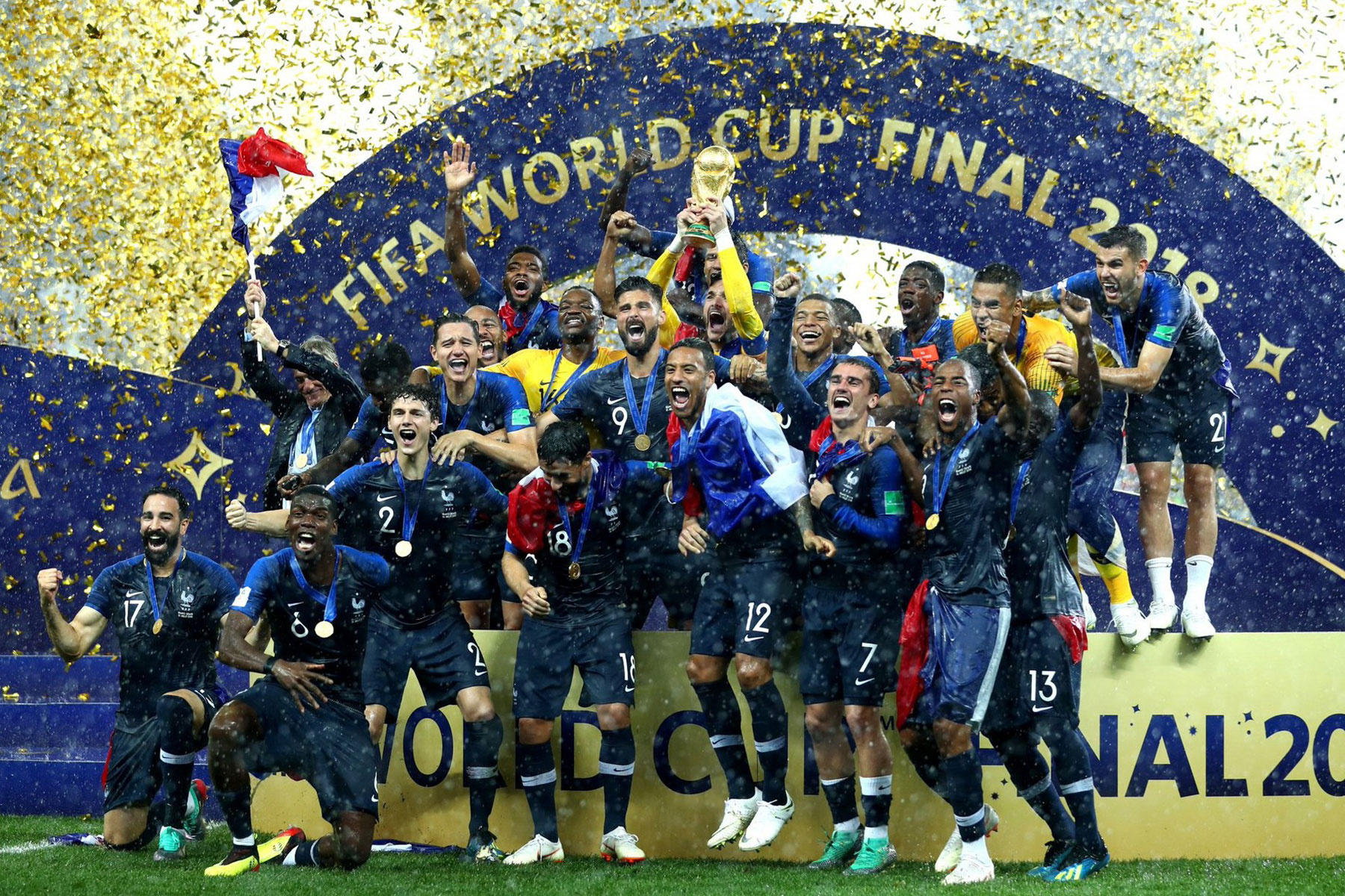  The image shows the French football team celebrating their victory in the 2018 FIFA World Cup. They are wearing their away jersey which is predominantly white with a blue stripe on the chest.